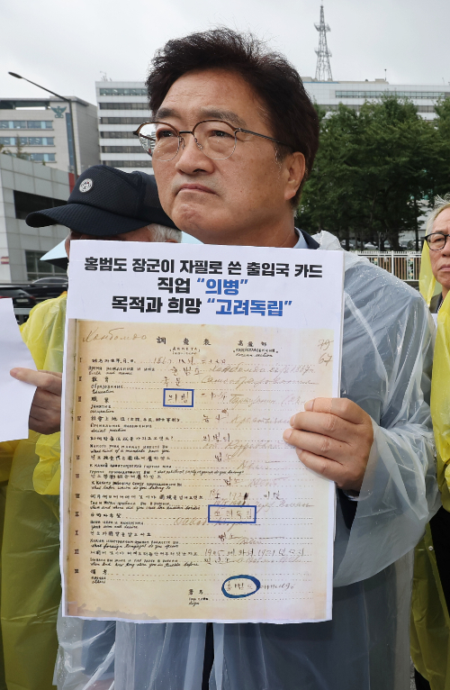 홍범도장군기념사업회 이사장인 더불어민주당 우원식 의원이 30일 서울 용산구 전쟁기념관 앞에서 열린 항일 독립전쟁 영웅 흉상 철거 백지화 및 책임자 처벌 요구 기자회견에서 홍범도 장군이 자필로 쓴 출입국 카드 손팻말을 들고 있다. 연합뉴스