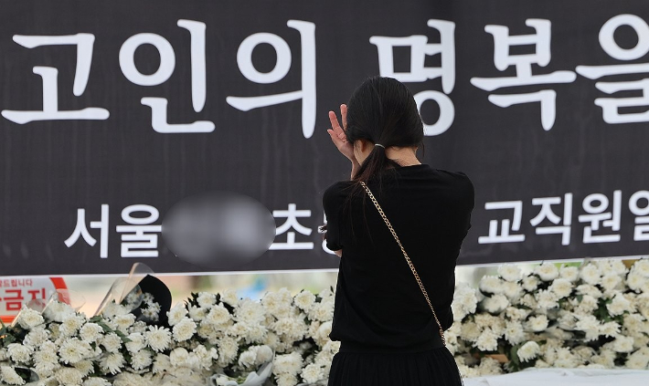  3일 서울 양천구의 한 초등학교 정문에 마련된 교사 A씨 추모공간을 방문한 시민이 눈물을 흘리고 있다. 연합뉴스