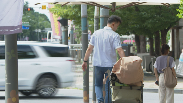 장상태 목사가 도심 속 외로운 사람들의 벗이 되기 위해 파라솔 설치 도구들을 실은 리어커를 끌고 걸어가고 있는 모습