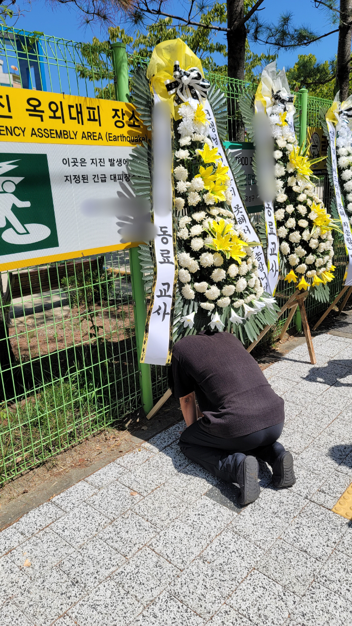 7일 숨진 대전 A 교사가 재직 중이던 한 초등학교에 근조 화환이 놓여있다. 무릎을 꿇은 채 슬퍼하는 동료교사의 모습. 독자 제공