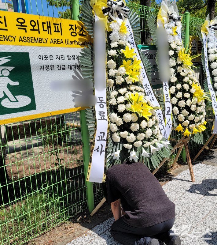 숨진 A 교사가 재직 중이던 한 초등학교에 근조 화환이 놓여있다. 무릎을 꿇은 채 슬퍼하는 동료교사의 모습. 독자 제공