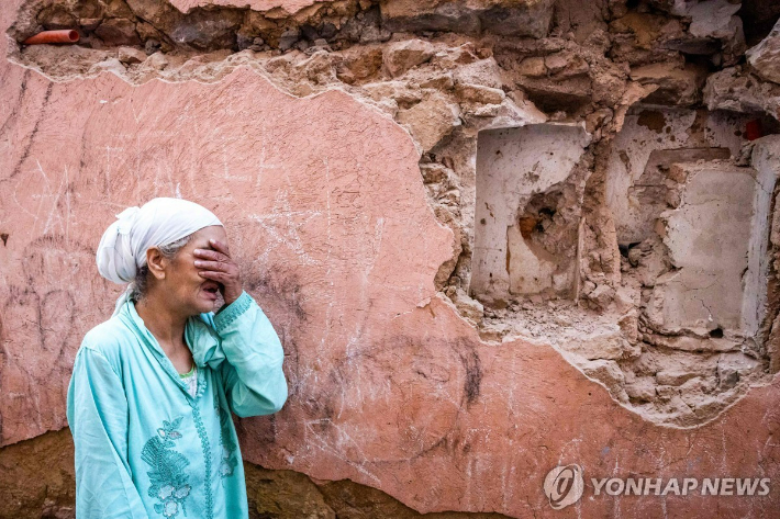 9일(현지시간) 모로코 마라케시의 구시가지에서 한 여성이 지진으로 파손된 집 앞에 서서 울고 있다. AFP, 연합뉴스