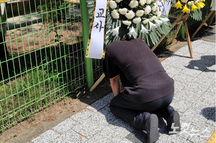 지난 7일 숨진 대전 A 교사가 재직 중이던 한 초등학교에 근조 화환이 놓여있다. 무릎을 꿇은 채 슬퍼하는 동료교사의 모습. 독자 제공