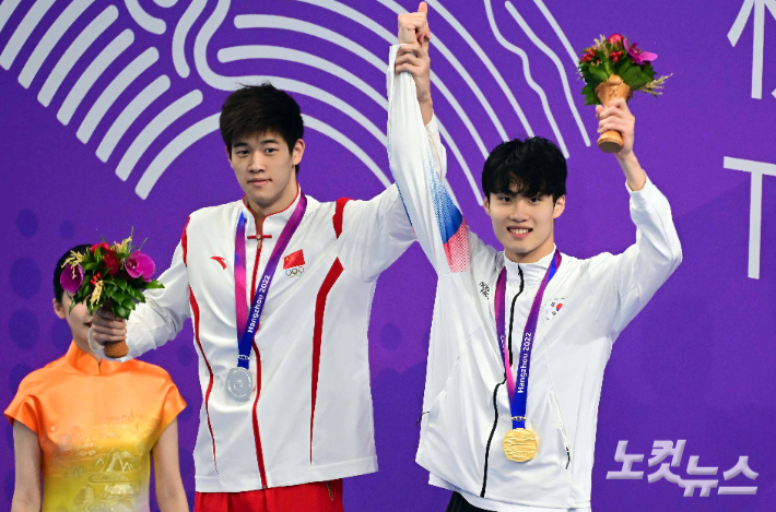 27일 중국 항저우 올림픽 스포츠센터 수영장에서 열린 2022 항저우 아시안게임 수영 남자 자유형 200ｍ 에서 은메달을 획득한 중국의 판잔러가 금메달을 획득한 황선우의 손을 올려주고 있다. 항저우(중국)=황진환 기자