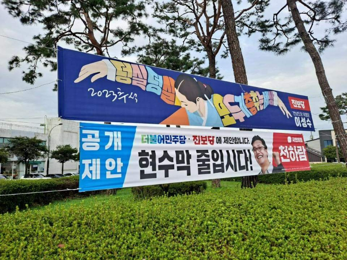 진보당 현수막 아래에 국민의힘이 제안한 현수막 줄입시다 현수막이 게시됐다. 진보당 제공