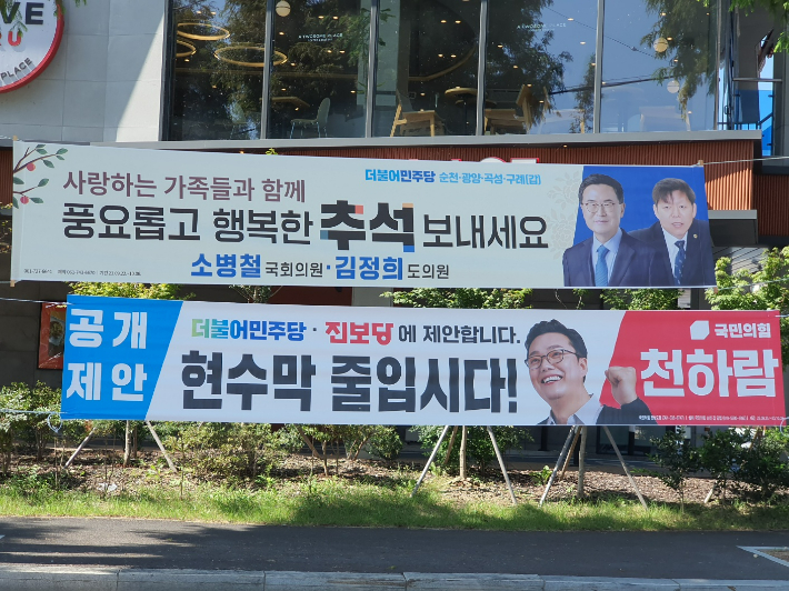 민주당 현수막 아래에 국민의힘이 제안한 현수막 줄입시다 현수막이 게시됐다. 고영호 기자