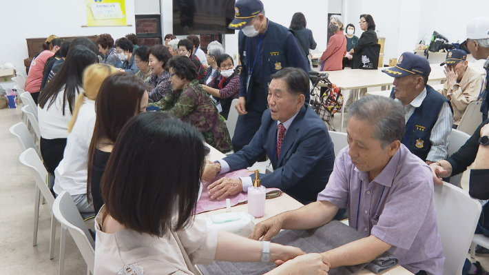 김포대학 뷰티아트과 미용동아리회가 어르신들의 손 마사지와 네일아트를 하고 있는 모습.  