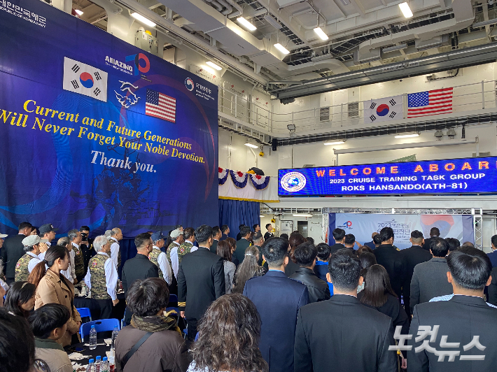 한산도함 격납고에서 열린 입항 환영행사에서 참석자들이 국기에 대한 경례를 하고 있다. 최철 기자