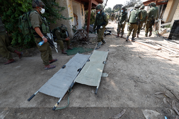이스라엘 군인들이 10일(현지시간) 팔레스타인 가자지구 인근에 있는 크파르 아자 키부츠에서 살해된 이스라엘인들의 시신을 수습하는 작업을 하고 있다. 연합뉴스