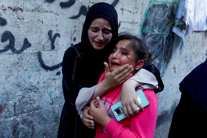 10일(현지시간) 팔레스타인 가자지구 남부 칸 유니스에서 무장 정파 하마스에 소속된 간부의 장례식이 열린 가운데 그의 딸이 한 여성에게 위로받고 있다.  연합뉴스 