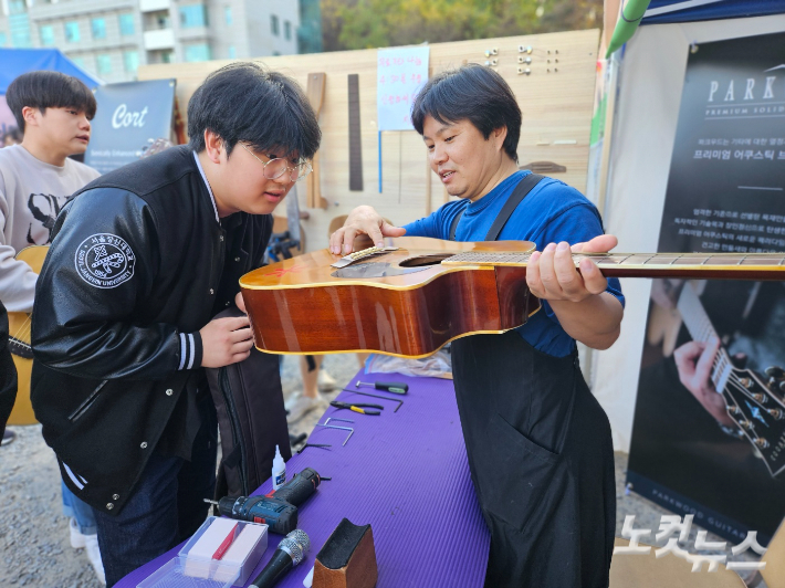 '기타 고치는 목사'로 알려진 일산 섬김의교회 구인수 목사(오른쪽)가 지난 2일 경기도 광주시 서울장신대 축제 현장을 찾아 신학생들의 기타를 무상으로 수리해주고 있다.