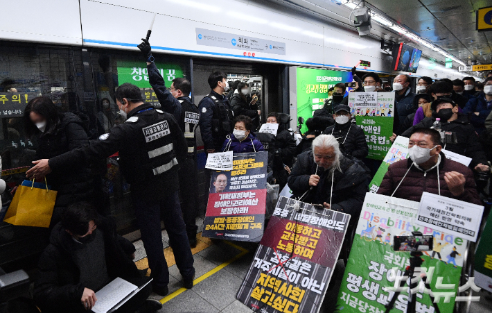 전국장애인차별철폐연대(전장연)가 지난 2월 20일 오전 서울 종로구 혜화역 지하철 승강장에서 박경석 대표 경찰 조사 출석 관련 최종 입장발표 기자회견을 하고 있는 가운데 시민들이 지하철에서 하차하고 있다. 류영주 기자