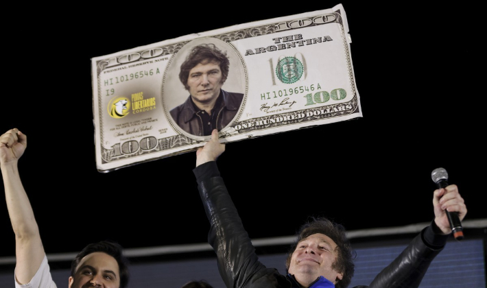 19일(현지시간) 아르헨티나 대선 결선에서 승리한 하비에르 밀레이 당선인이 대선 결선 투표를 앞둔 지난 16일 코르도바에서 연 마지막 유세에서 100달러 디자인에 자신의 얼굴을 인쇄한 피켓을 들고 환호하는 모습. 연합뉴스