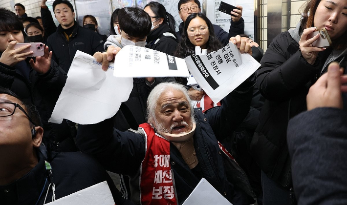박경석 전국장애인차별철폐연대(전장연) 대표가 28일 오전 서울 종로구 혜화역 승강장에서 열린 '불법폭력 연행 입장 발표 및 국가인권위원회 진정 기자회견'에서 퇴거 요청을 받은 뒤 진정서를 찢고 있다. 연합뉴스