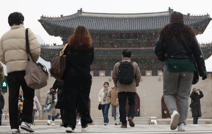 서울 종로구 광화문광장 일대에 눈이 내리는 가운데 시민들이 걸어가고 있다. 연합뉴스