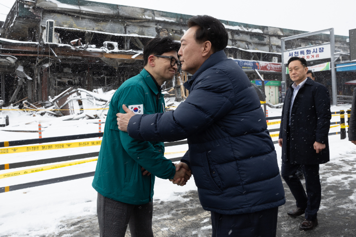 윤석열 대통령이 23일 충남 서천군 서천읍 서천특화시장 화재 현장에서 국민의힘 한동훈 비상대책위원장과 만나 악수하고 있다. 연합뉴스