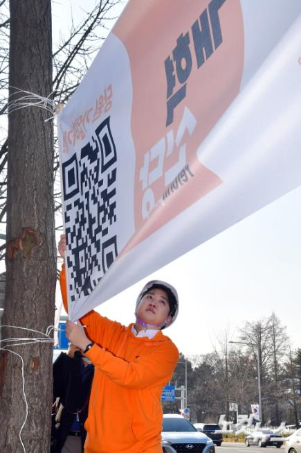 개혁신당 이준석 대표가 26일 서울 여의도 국회의사당 앞 가로수에 정당 홍보 현수막을 설치하고 있다.
