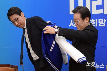 이훈기 전 OBS기자에게 당 점퍼 전달하는 이재명 대표