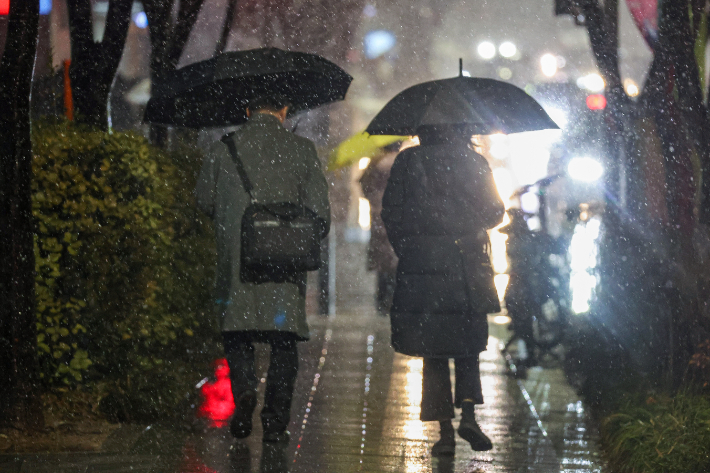 수도권을 비롯한 중부지역에 대설주의보가 내린 21일 밤 서울 서대문구 연세대학교 앞에서 시민들이 우산을 쓰고 이동하고 있다. 연합뉴스