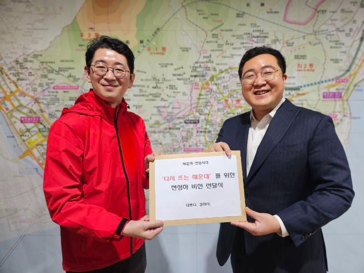 전성하 예비후보(오른쪽)가 주진우 예비후보(왼쪽)에게 자신의 공약이 담긴 정책자료집을 전달하고 있다. 주 후보 캠프 제공