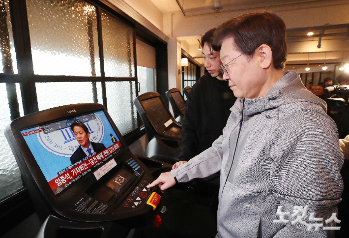 이재명 더불어민주당 대표가 28일 오전 서울 서대문구 매직짐 휘트니스에서 러닝머신을 이용하는 중, 화면에 임종석 전 대통령비서실장의 공천 관련 기자회견 모습이 보이고 있다. 국회사진취재단