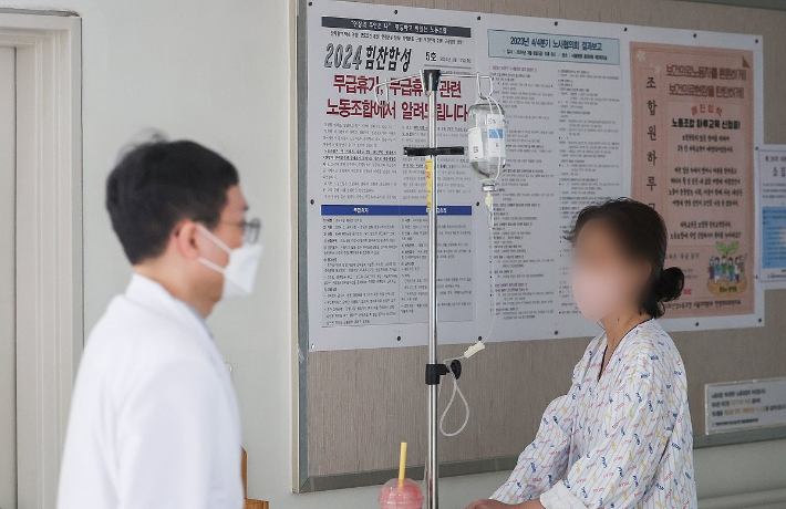 17일 오전 서울 시내 한 대학병원에서 한 의료 관계자와 환자가 전공의 이탈로 인한 무급휴가 관련 노조 게시물을 지나치고 있다. 연합뉴스