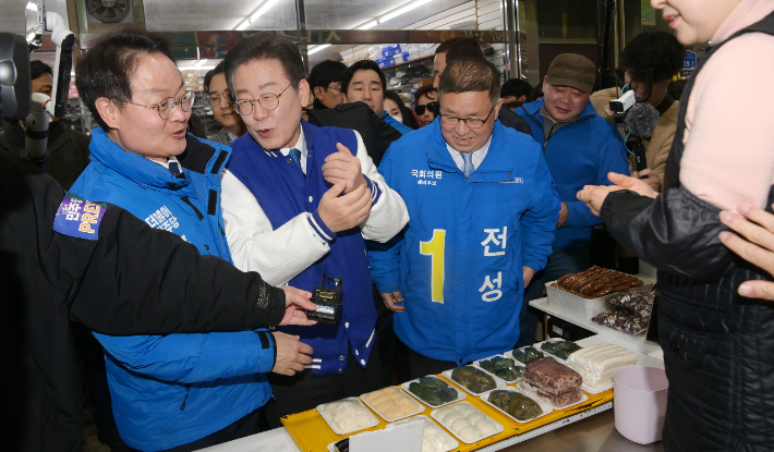 더불어민주당 이재명 대표가 19일 오전 강원 춘천시 중앙시장을 방문해 떡을 사 먹으며 상인들과 인사하고 있다. 연합뉴스