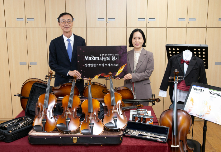 지난해 11월 동서식품 최상인 상무(왼쪽)가 맥심 사랑의 향기 프로그램을 통해 인천상정초등학교 상정엔젤스트링 오케스트라에 악기와 단복 등을 전달한 뒤 기념촬영을 하고 있다. 동서식품 제공 