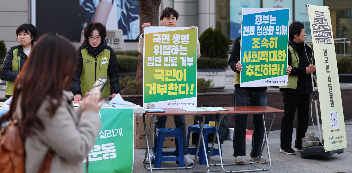 지난 13일 오후 서울 종로구 동화면세점 앞에서 보건의료노조가 의사들의 진료거부 중단을 촉구하는 범국민 서명운동을 하고 있다. 연합뉴스