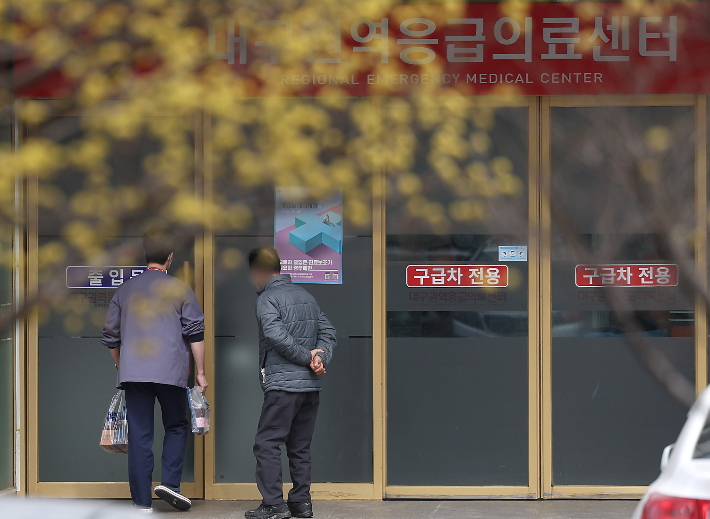 지난 17일 대구 한 대학병원 응급실 앞에 산수유가 만개한 가운데 의료관계자가 이동하고 있다. 연합뉴스