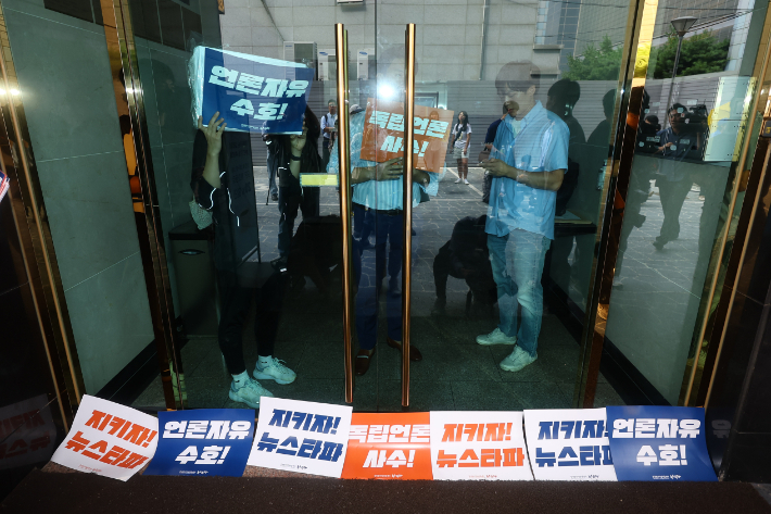 뉴스타파 직원들이 지난해 9월 14일 오전 대장동 허위 보도 의혹으로 압수수색 중인 서울 중구 뉴스타파 출입문 앞에 팻말을 붙이고 있다. 연합뉴스