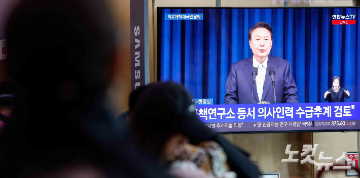 의대 2천명 증원 방침을 둘러싼 의정 갈등이 장기화되고 있는 1일 서울 중구 서울역에서 시민들이 윤석열 대통령의 의료 개혁과 관련한 대국민 담화를 보고 있다. 박종민 기자