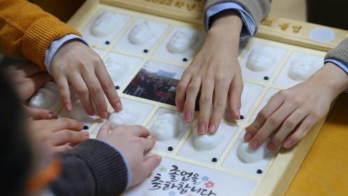지난해 1월 13일 대구시 남구 시각장애 학생을 위한 교육기관인 대구광명학교에서 열린 2022학년도 졸업식에서 졸업생들이 3D 프린터로 제작된 졸업앨범에서 친구 얼굴을 손끝으로 찾아보고 있다. 연합뉴스