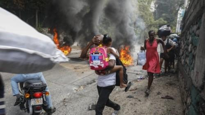 지난 2월 5일(현지시간) 아이티 수도 포르토프랭스에서 행인들이 불붙은 폐타이어 옆을 황급히 지나가고 있다. 아리엘 앙리 총리 사임을 요구하는 시위대는 도로를 점거한 채 폐타이어에 불을 지르거나 주요 시설물에 돌을 던지면서 격렬한 시위를 벌였다. 연합뉴스