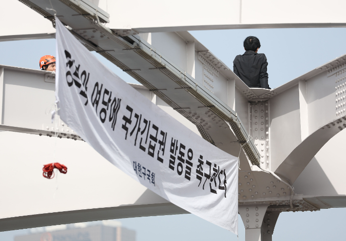 신원불명의 남성이 17일 오전 서울 용산구 한강대교 아치 위에 올라가 있다. 연합뉴스 