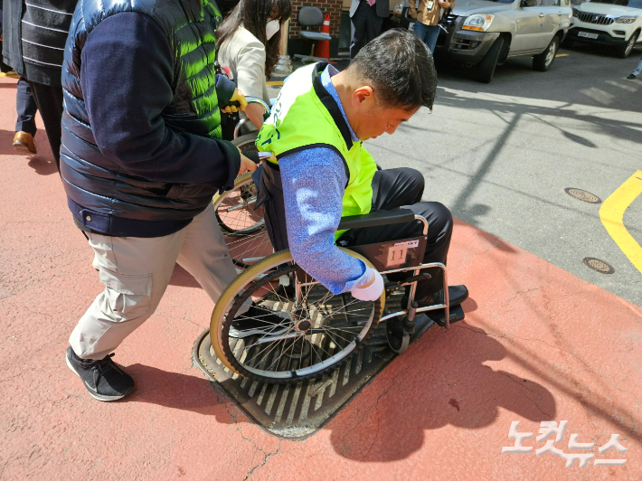 오은택 부산 남구청장이 탄 수동휠체어가 하수구 맨홀 뚜껑에 빠져 옴짝달싹 못하고 있다. 김혜민 기자