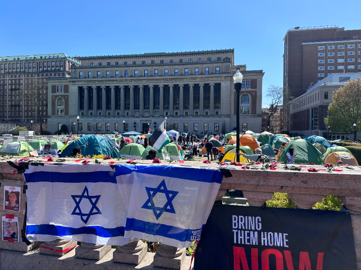 25일(현지시간) 미국 뉴욕 컬럼비아대 교정 이스라엘 국기 너머로 가자 전쟁을 반대하는 학생들이 텐트를 치고 농성을 벌이고 있다. 연합뉴스