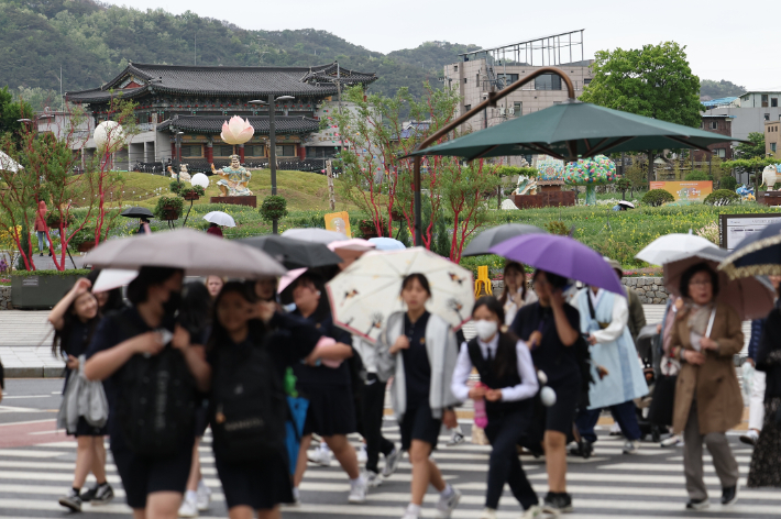 서울 전역에 비가 내린 7일 오후 서울 종로구 송현동공원 인근에서 시민들이 우산을 쓰고 이동하고 있다. 연합뉴스