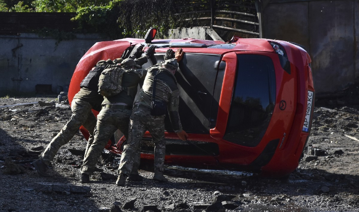 우크라이나 병사들이 8일(현지시간) 러시아군의 미사일 공격을 받은 자포리자에서 뒤집힌 차를 바로 세우고 있다. 연합뉴스