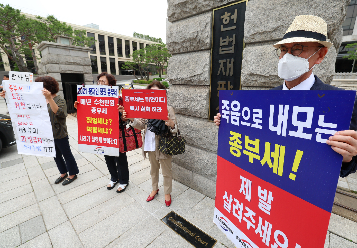 지난달 30일 서울 종로구 헌법재판소 앞에서 시민들이 종부세 규탄 피켓을 들고 서 있는 모습. 연합뉴스