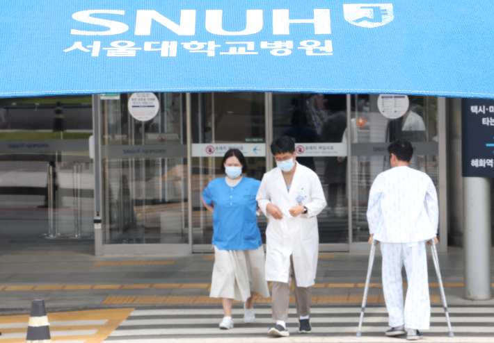 서울의대·서울대병원 교수 비상대책위원회(비대위)는 전공의 사태가 해결되지 않을 경우 오는 17일부터 응급실과 중환자실 등 필수 부서를 제외한 전체 휴진에 들어간다고 6일 밝혔다. 7일 병원 앞을 걸어가는 의료진 모습. 연합뉴스