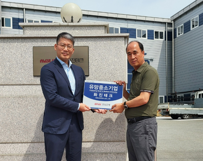 BNK경남은행 제언호 부장(사진 왼쪽)과 화진테크 이하진 대표가 '유망중소기업 현판'을 들고 기념촬영을 하고 있다. BNK경남은행 제공