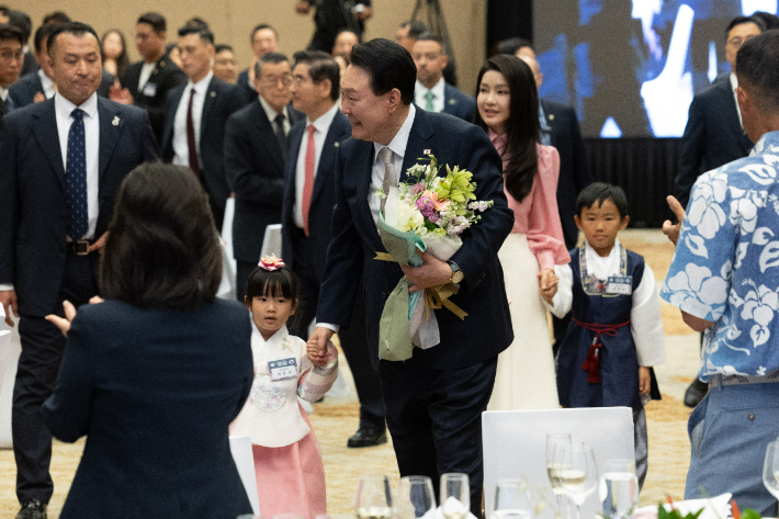 윤석열 대통령과 김건희 여사가 8일(현지시간) 미국 하와이 호놀룰루 쉐라톤 호텔에서 열린 동포간담회에 화동과 함께 입장하고 있다. 연합뉴스 