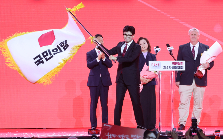 국민의힘 한동훈 당대표 당선자가 23일 오후 경기도 고양시 킨텍스에서 열린 국민의힘 제4차 전당대회에서 황우여 비상대책위원장으로부터 당기를 전달받아 흔들고 있다. 연합뉴스