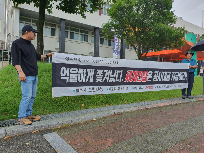 광진건설 측이 순천시 앞에서 공사 대금 지급을 촉구하는 현수막을 들고 있다. 고영호 기자