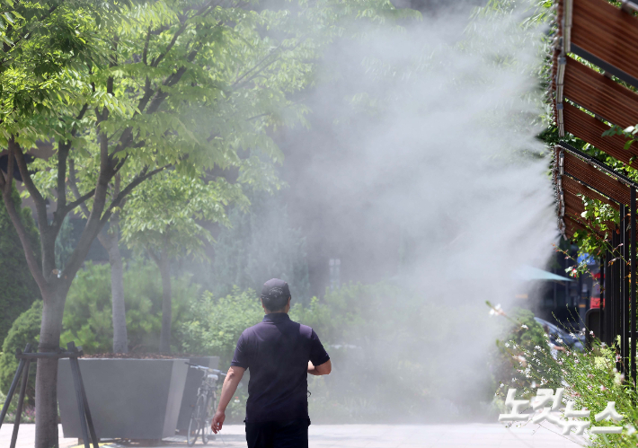  시민들이 쿨링포그(안개형 냉각 장치) 아래를 지나가고 있다. 황진환 기자
