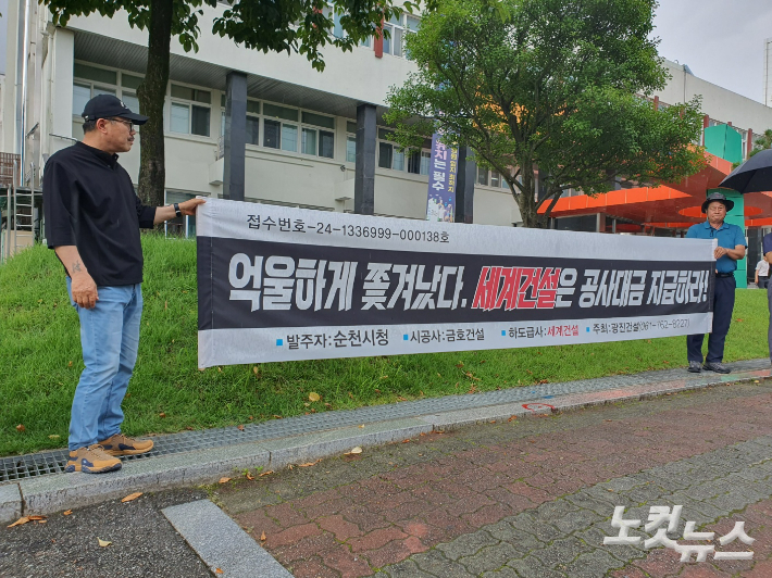 광진건설 측이 순천시청 앞에서 공사 대금 지급을 촉구하는 현수막을 들고 있다. 고영호 기자