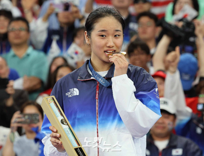 안세영이 5일(현지 시간) 파리 라 샤펠 아레나에서 열린 2024 파리올림픽 배드민턴 여자 단식 결승전에서 중국 허빙자오를 꺾은 뒤 시상식에서 금메달을 깨무는 세리머니를 펼치고 있다. 파리= 올림픽사진공동취재단/황진환 기자