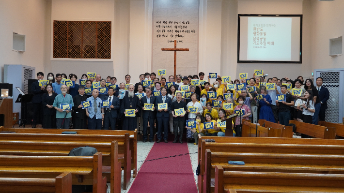 한반도 평화통일 남북공동 기도주일예배 참석자들이 예배 후 '평화를 원한다' 등의 문구가 적힌 손 피켓을 들고 기념사진을 촬영했다. 사진 한국기독교교회협의회 제공