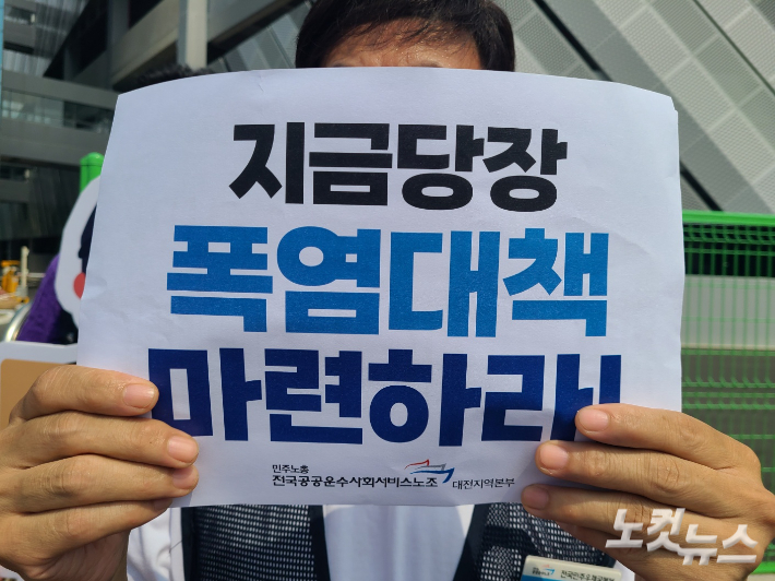 12일 한진 스마트 메가허브 터미널 앞에서 진행된 기자회견에서 한 참가자가 '지금 당장 폭염대책 마련하라'고 적힌 손피켓을 들고 있다. 김정남 기자